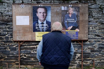 A man stands in front of French presidential campaign posters