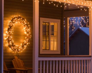A Christmas porch decorated with wreath and copper fairy lights