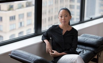 Pauchi Sasaki sitting on a black chair in front of a window