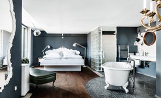 Suites feature gunmetal grey walls, Anglepoise lamps, white marble table tops, dark parquetry and round, leather rimmed Jacques Adnet-style mirrors