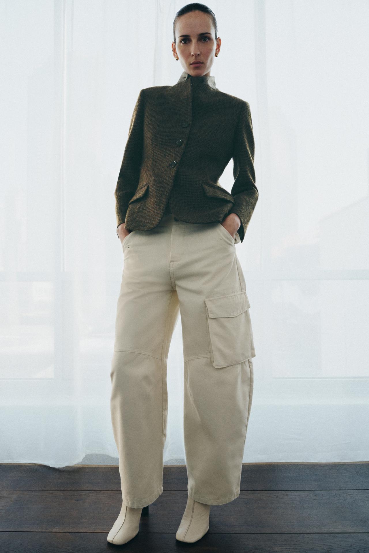 Model is wearing a tailored blazer with white barrel-leg jeans and square toe white boots.