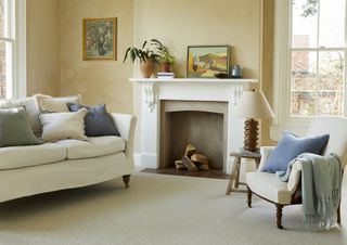 A living room with a neutral toned carpet and a fireplace