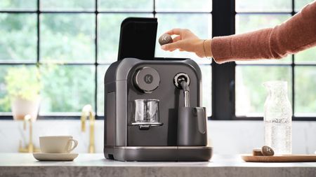 Woman inserting coffee tablet in Keurig Alta coffee maker