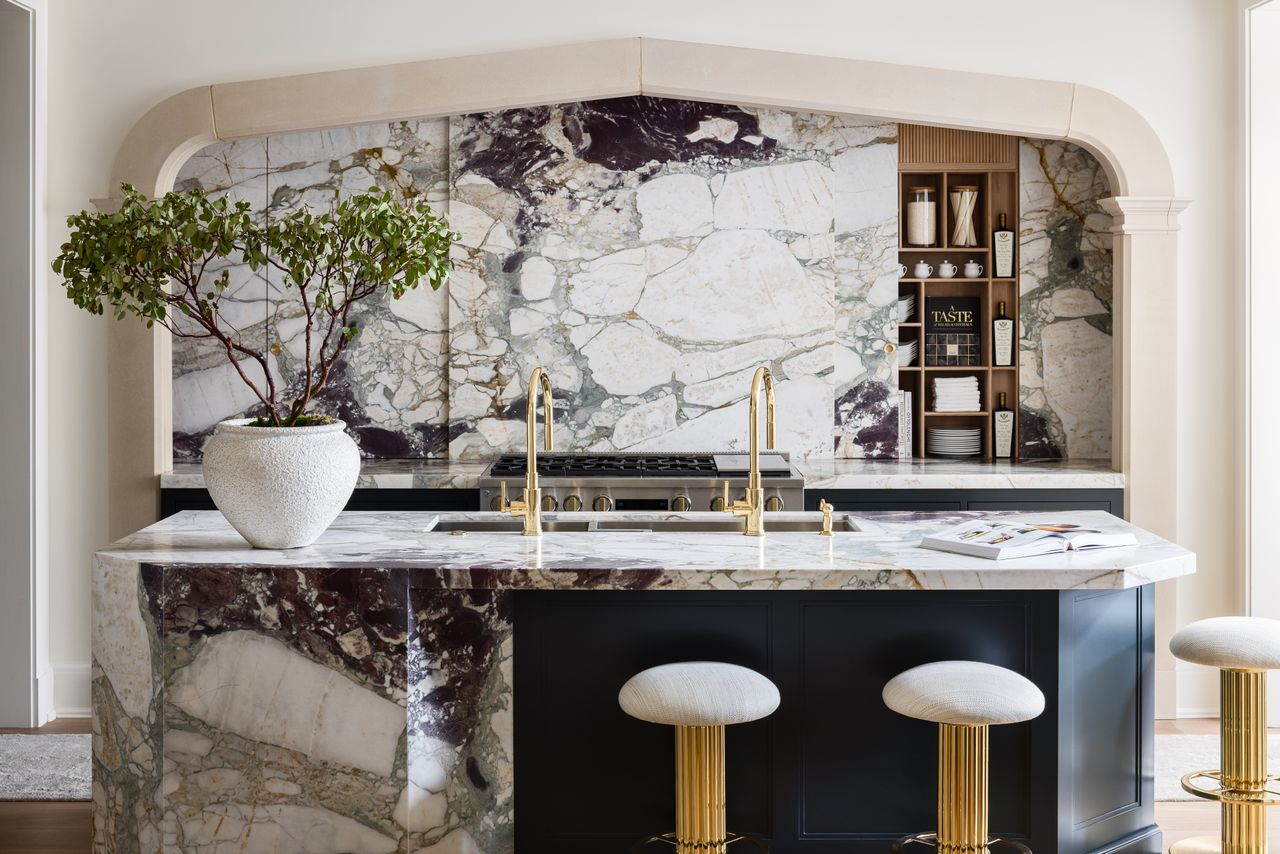 A kitchen with marble backsplash and gold hardware