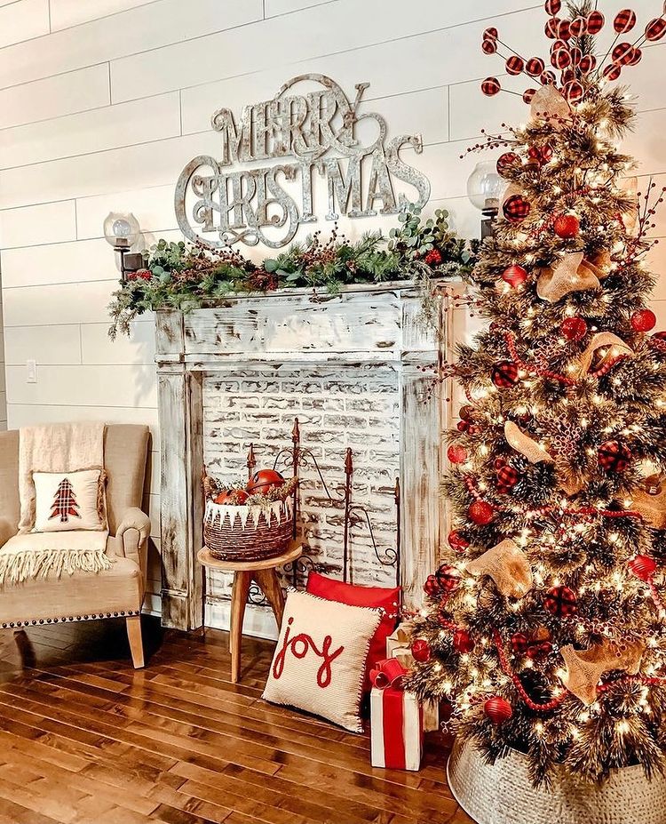 Decorated Christmas tree next to white festive mantel with garland and silver signage