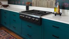 close up of teal kitchen with white worktops and hob