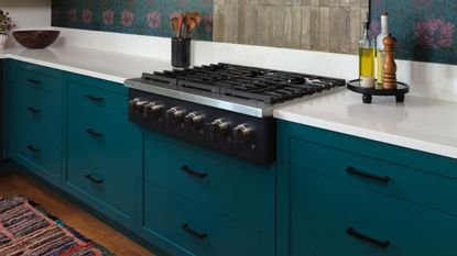close up of teal kitchen with white worktops and hob