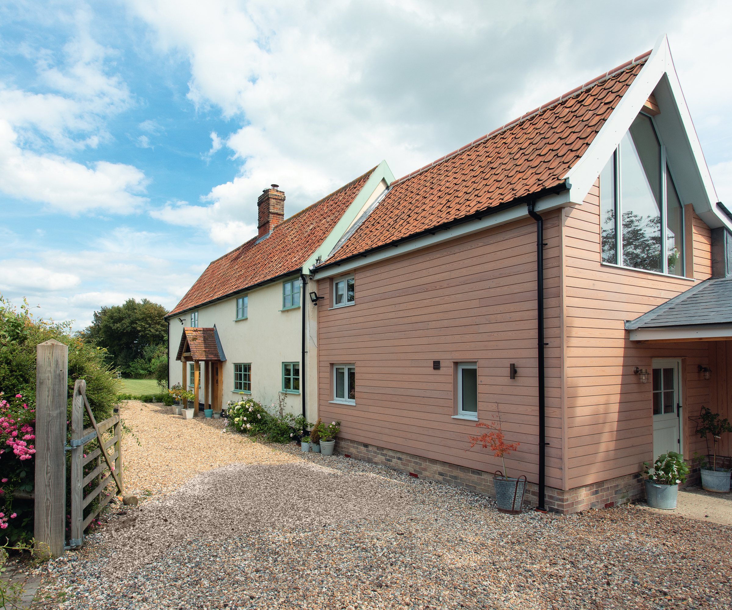 timber clad double storey house extension to cream rendered cottage with tiled roof
