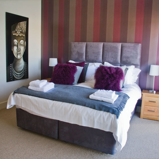 bedroom with grey headboard and painting and faux fur cushion