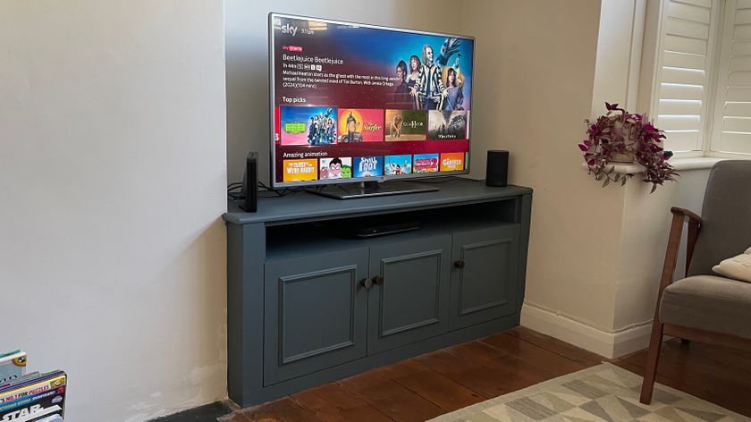 A blue TV cabinet shot at a 3/4 angle with a TV on it. On screen is the Sky menu screen of Beetlejuice Beetlejuice.