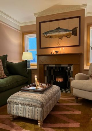 Cozy beige and brown living room with a fish painting hanging over the fireplace an da forest green couch