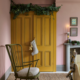 A yellow painted bedroom wardrobe with christmas stocking hung from wardrobe door knob