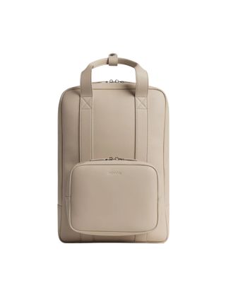 A beige backpag with a front, detachable pochet pocket and visible stitching.