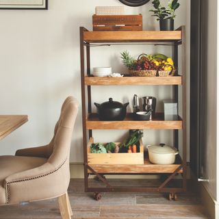 Dining room with a wooden shelving unit on castors storing utensils and cast iron pan