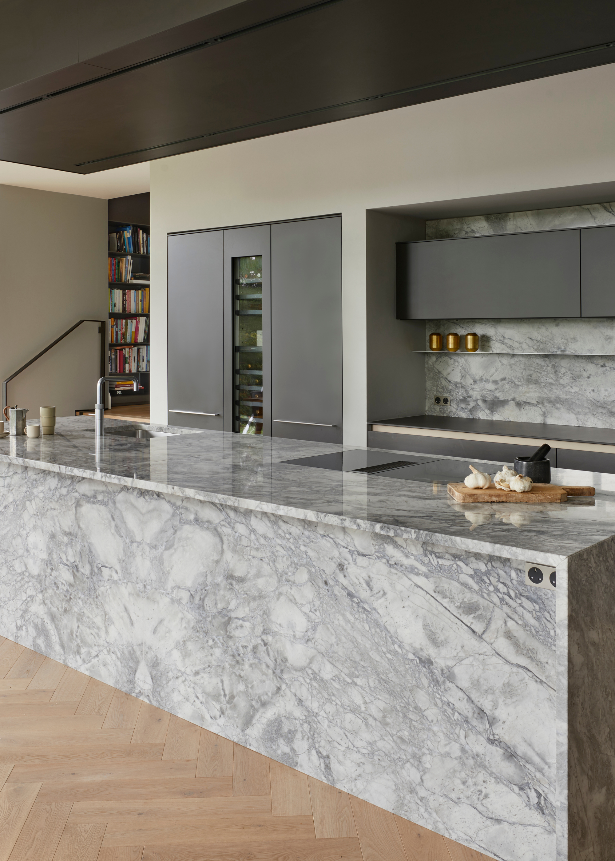 a modern luxury kitchen with a large marble kitchen island and sleek, grey cabinetry