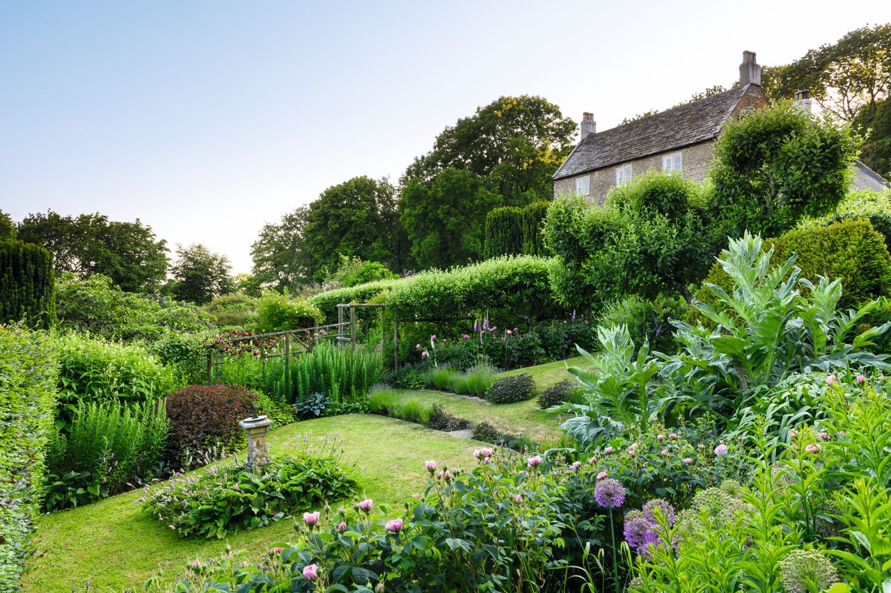 The old farmhouse stands above the sundial garden with, just visible in the top left, the pair of 150-year-old Irish yews that have recently been reclipped.