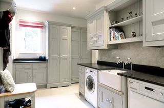 Large utility room with Belfast sink, shaker style grey storage units, open shelving, washing machine and tumble dryer as a n idea for designing a utility room