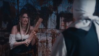 Kailey Hyman as Brooke fearfully holding a plank in front of David Howard Thornton as Art the Clown in Terrifier 2