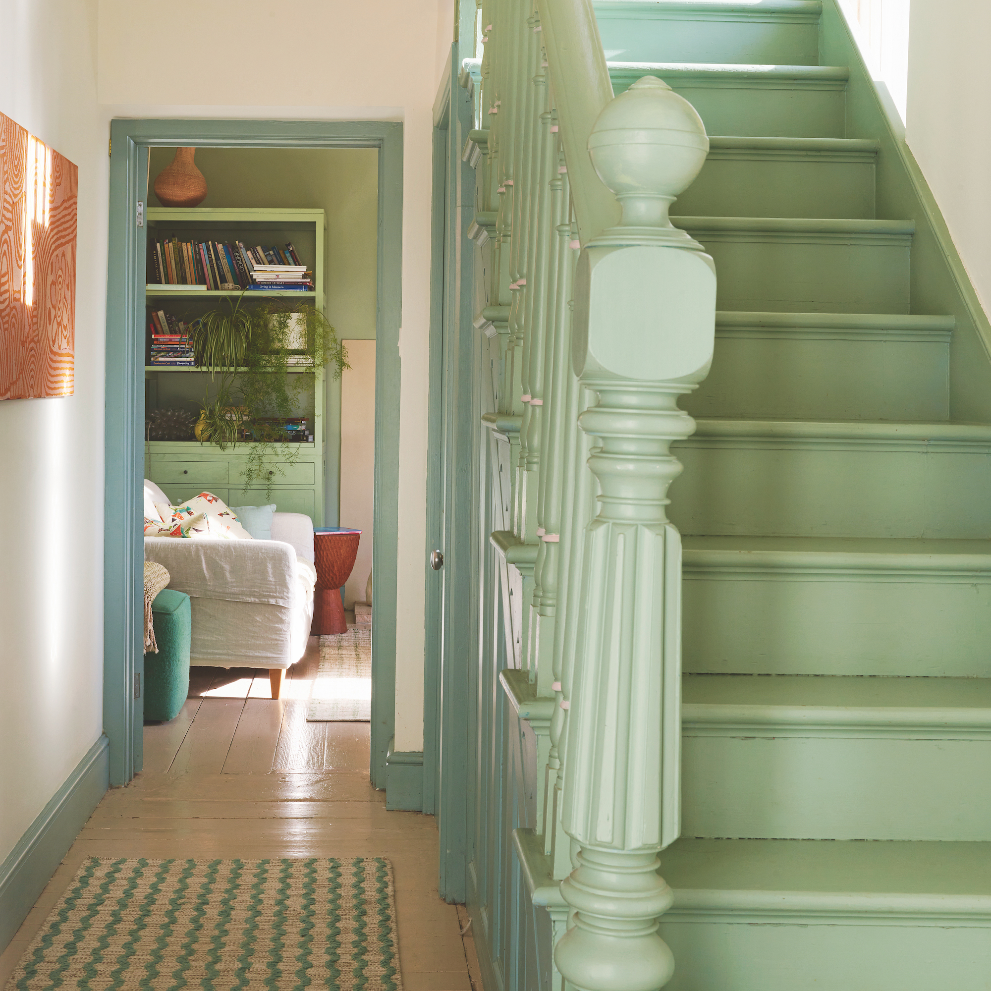 hallway of house looking through to living room and green painted staircase
