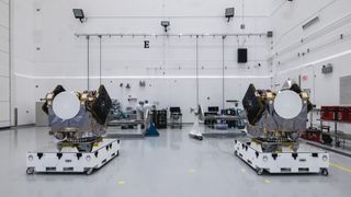 Two engines sit on white platforms in a clean warehouse
