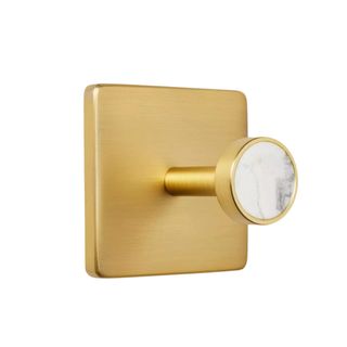 A gold square wall hook with a marble circle