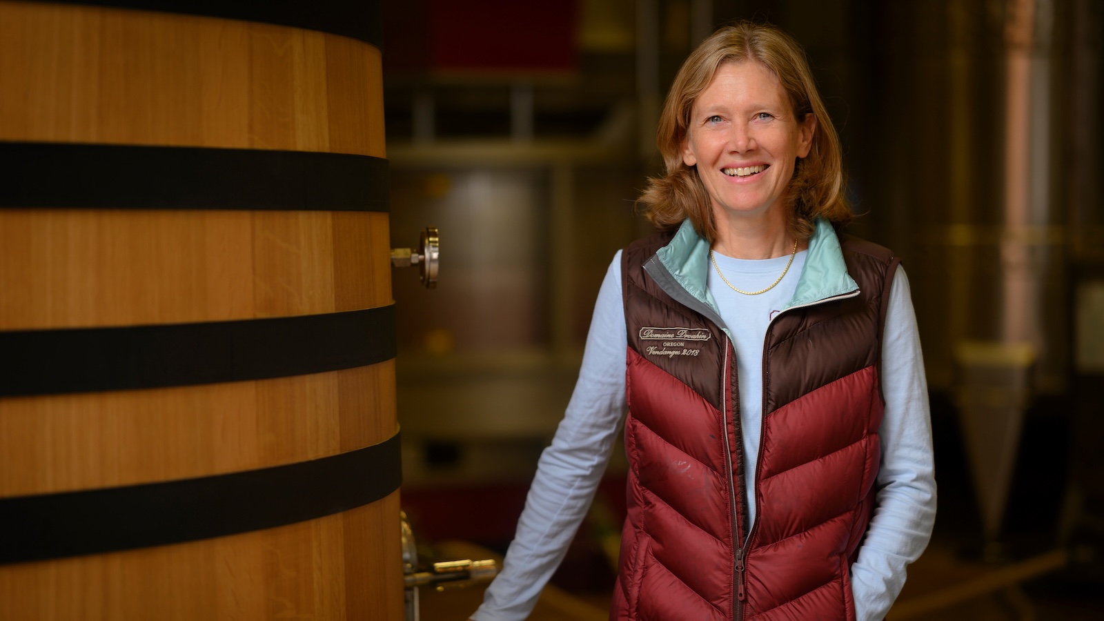 A portrait of Domaine Drouhin Oregon winemaker V&amp;eacute;ronique Boss-Drouhin standing next to a large, upright wood cask.