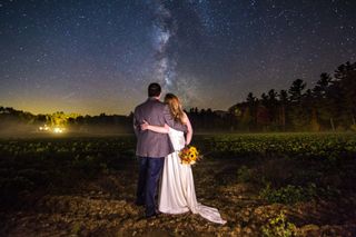 A bride and groom pose for a wedding photo with the Milky Way in the Wight Mountains of New Hampsire.