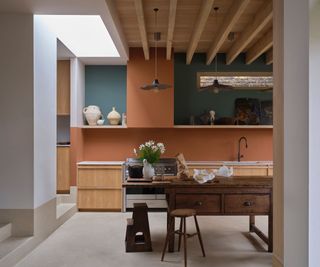 modern kitchen with terracotta wall, wooden cabinets, and butcher's block, wood beams on the ceiling