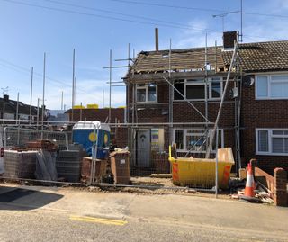 The front view of a semi-detached home that is having a blockwork extension added to the side