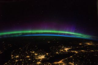 Astronaut Kate Rubins captured this photo from the International Space Station and shared it with the caption, "Green aurora with purple highlights compliment the city lights in the Great Lakes region." The photo may have partially inspired the colors of the Expedition 64 crew patch.