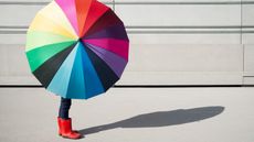 A person takes shelter under a colorful umbrella.