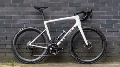 A white Specialized S-Works Tarmac SL8 stands against a wall