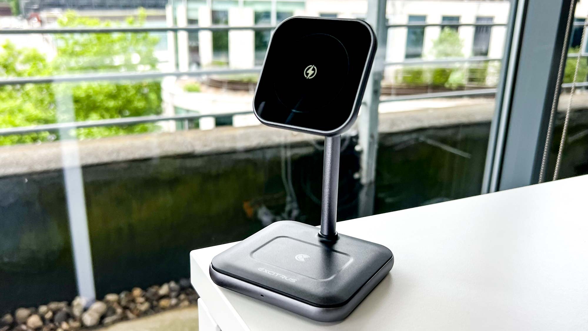 The Excitrus 3n1 Wireless Charging Stand, stood on a desk near a window