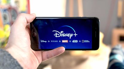 Disney stock represented through someone holding a phone showing the Disney+ app