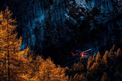 A helicopter flies over an Italian forest.