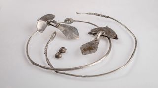 Silver necklaces and brooches against a gray background