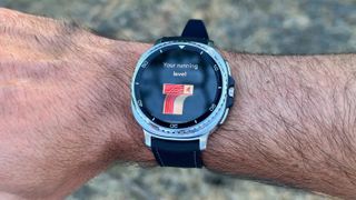 The Samsung Galaxy Watch 8 Classic worn on a wrist outside, the display showing "Your running level" and a stylized orange number 7 underneath.