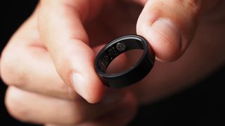 A close-up picture of a hand holding a black smart ring