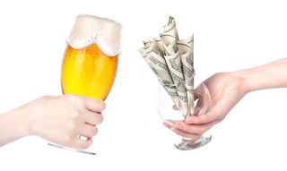 Two hands come together in a toast, with a beer glass and a glass full of money