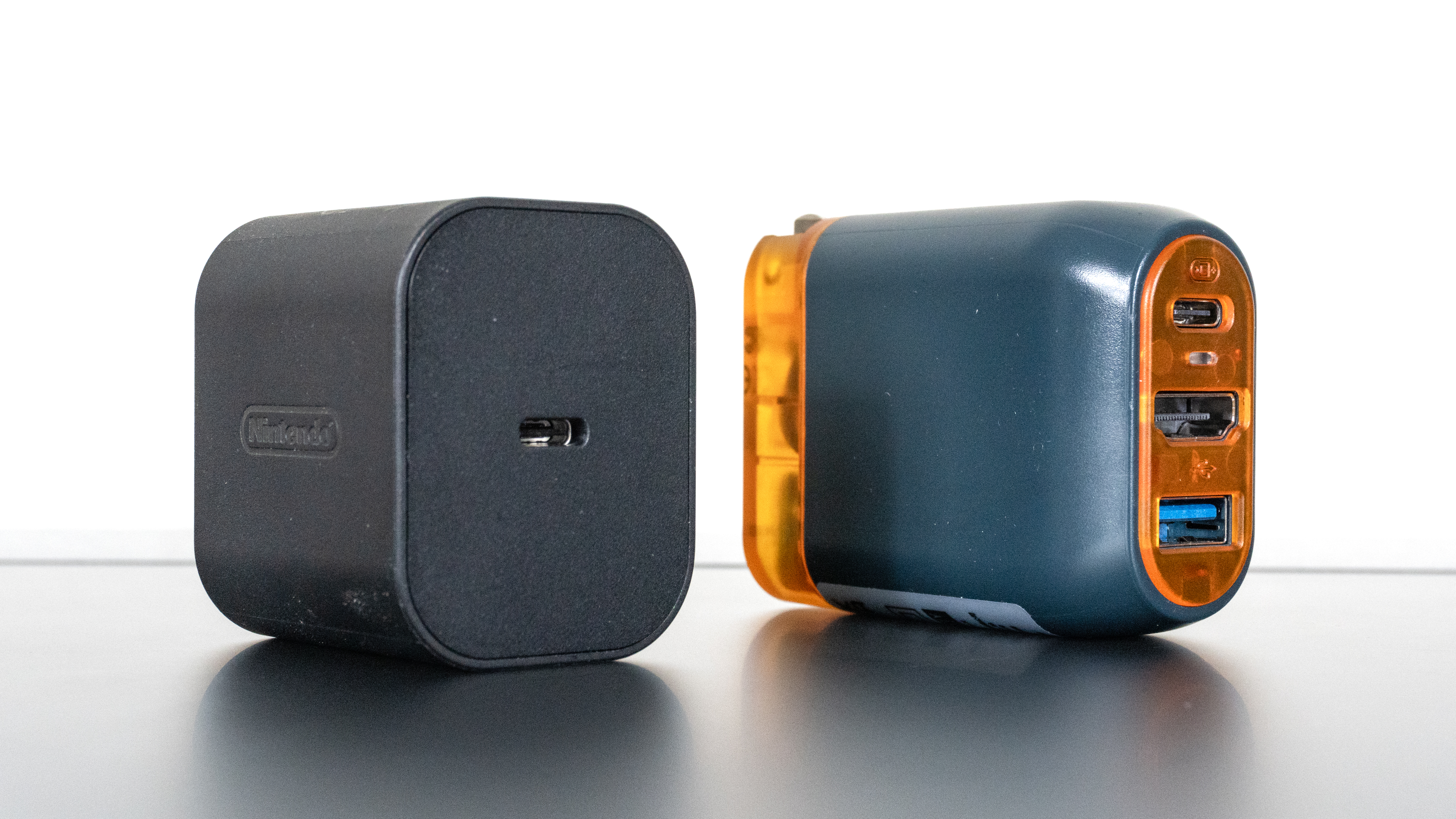 An official Nintendo Switch 2 power adapter next to the Genki Covert Dock 3