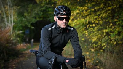 Male rider wearing Castelli Espresso Air Jacket in black on a leafy country lane