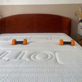 Otty Pure Plus mattress with orange dumbbells on mattress to show support