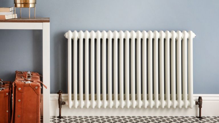 An off-white radiator in room with suitcases