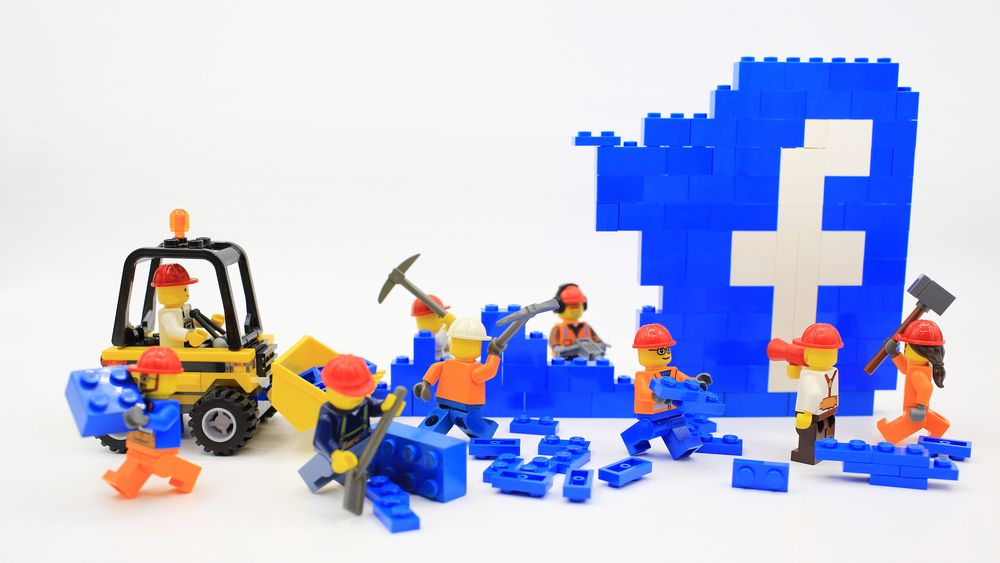 Lego builders dismantling the Facebook logo