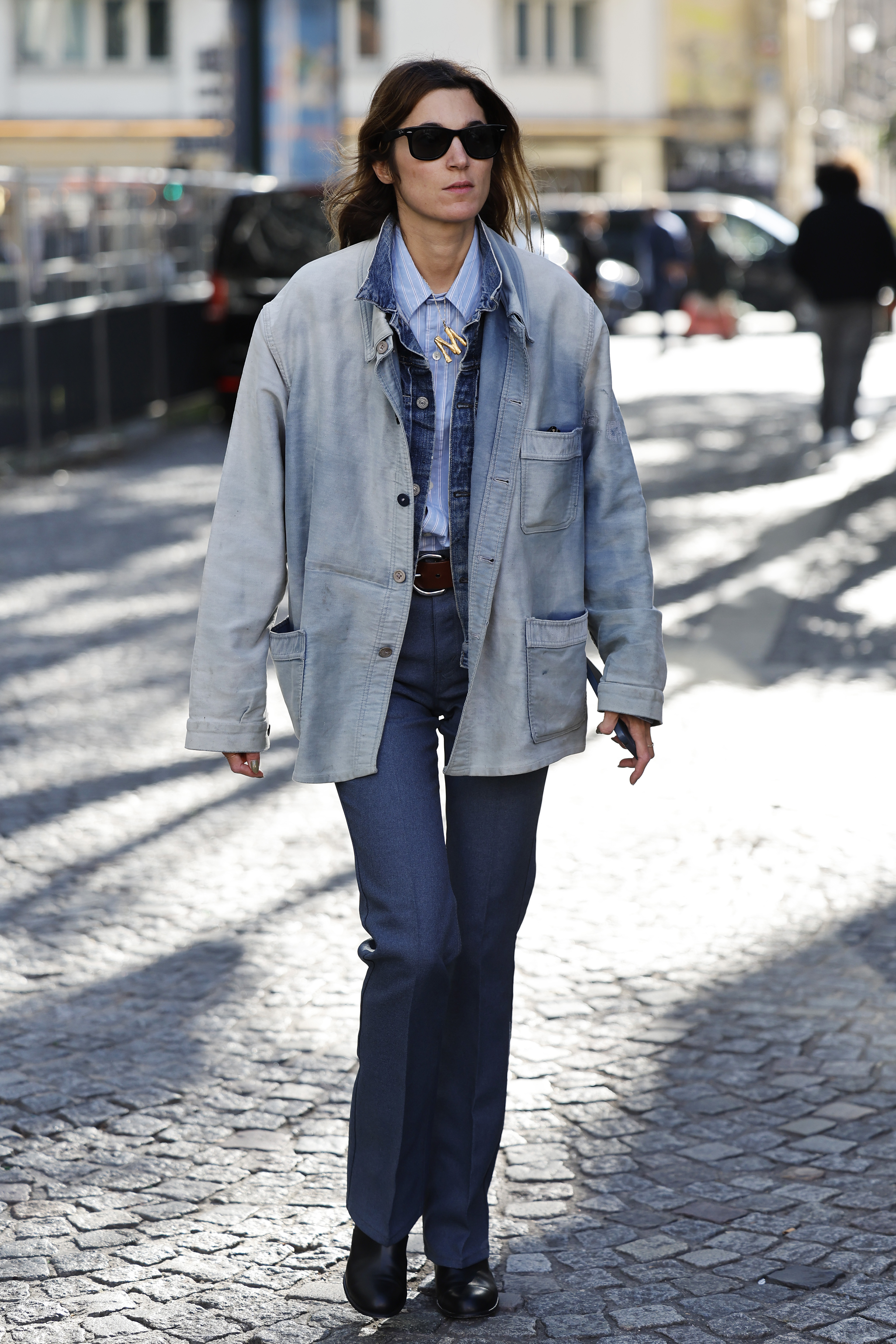 PARIS, FRANCE - SEPTEMBER 30: A guest wears light blue striped shirt, blue denim jacket underneath a light wash denim jacket, blue trousers, brown belt, black sunglasses, outside Zomer, during the Womenswear Spring Summer 2026 as part of Paris Fashion Week on September 30, 2025 in Paris, France. (Photo by Claudio Lavenia/Getty Images)