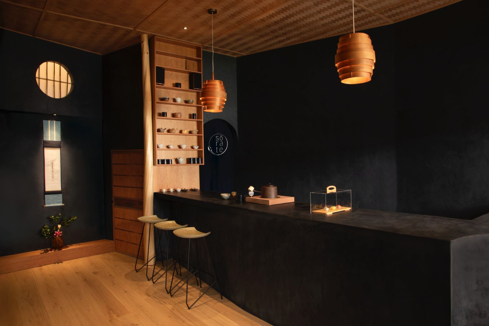 A matcha bar with dark walls and warm wooden elements across the floor, shelving, and ceiling.