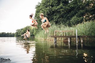 'Summer day: three young adults jump from jetty into lake' by fotografixx