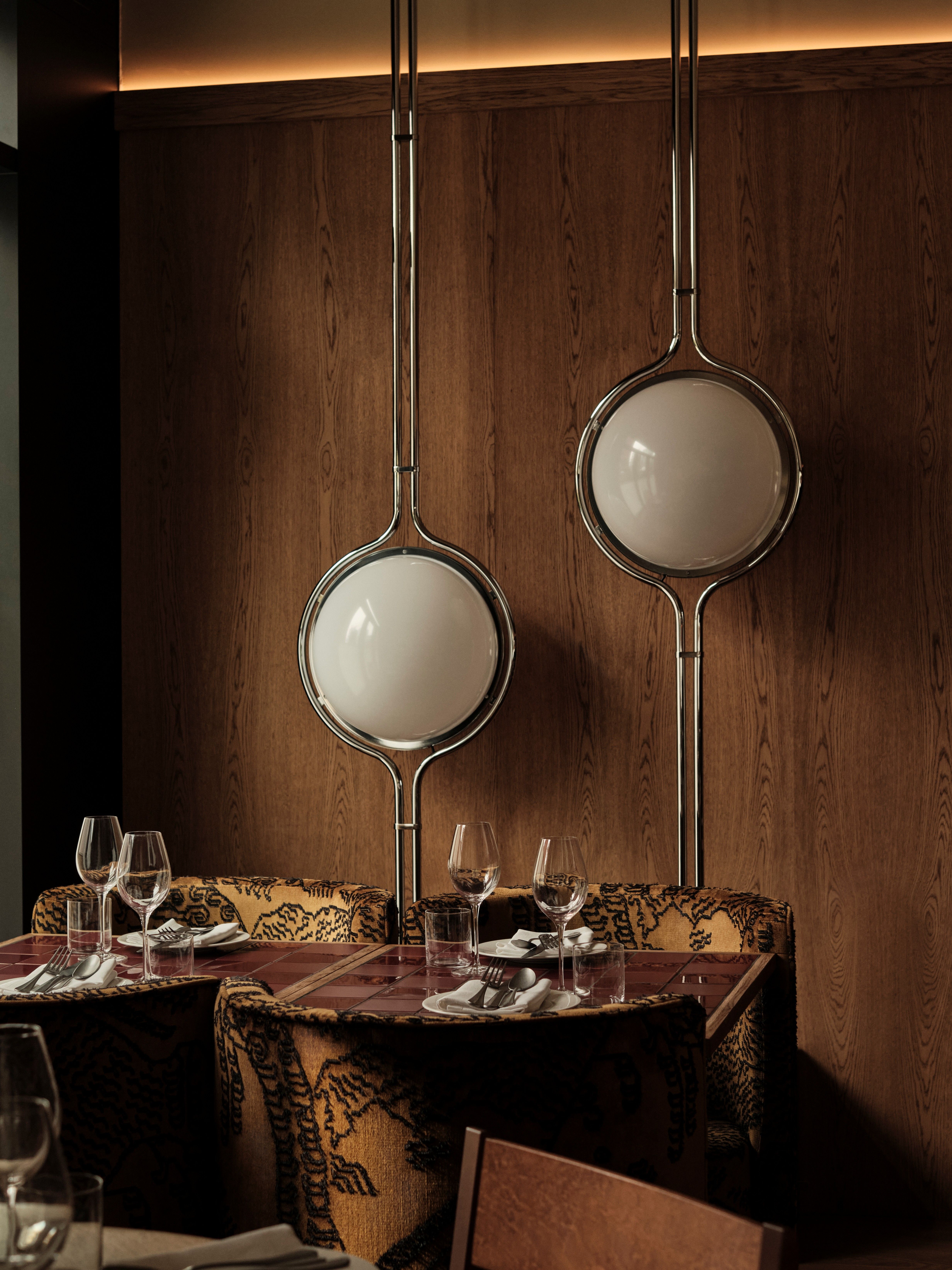 Interior shots of a restaurant with wooden surfaces, warm, sculptural lighting, lacquered and tiled surfaces, and a retro-inspired ambiance.