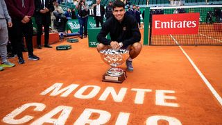 Carlos Alcaraz kneels on court after winning the Monte Carlos Masters 2025