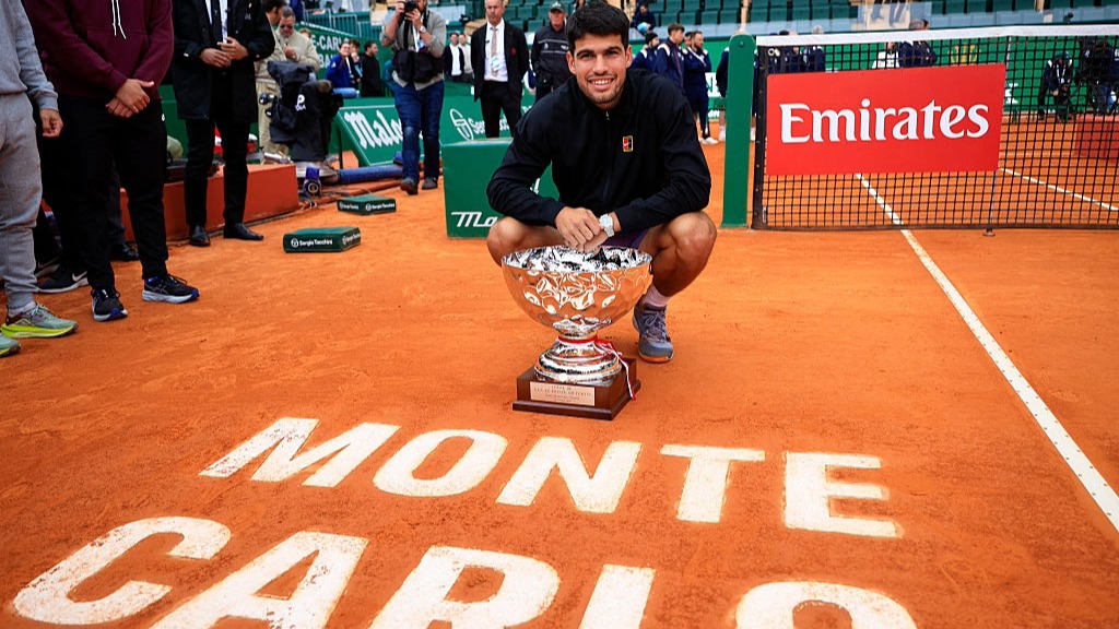 Carlos Alcaraz kneels on court after winning the Monte Carlos Masters 2025